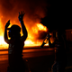 In this Aug. 24, 2020, file photo, protesters walk past police with their arms up, in Kenosha, Wis., as a building burns in the background. The federal government deliberately targeted Black Lives Matter protesters via heavy-handed criminal prosecutions in an attempt to disrupt and discourage the global movement that swept the nation last summer in the wake of the police killing of George Floyd, according to a new report released Wednesday, Aug. 18, 2021, by The Movement for Black Lives.